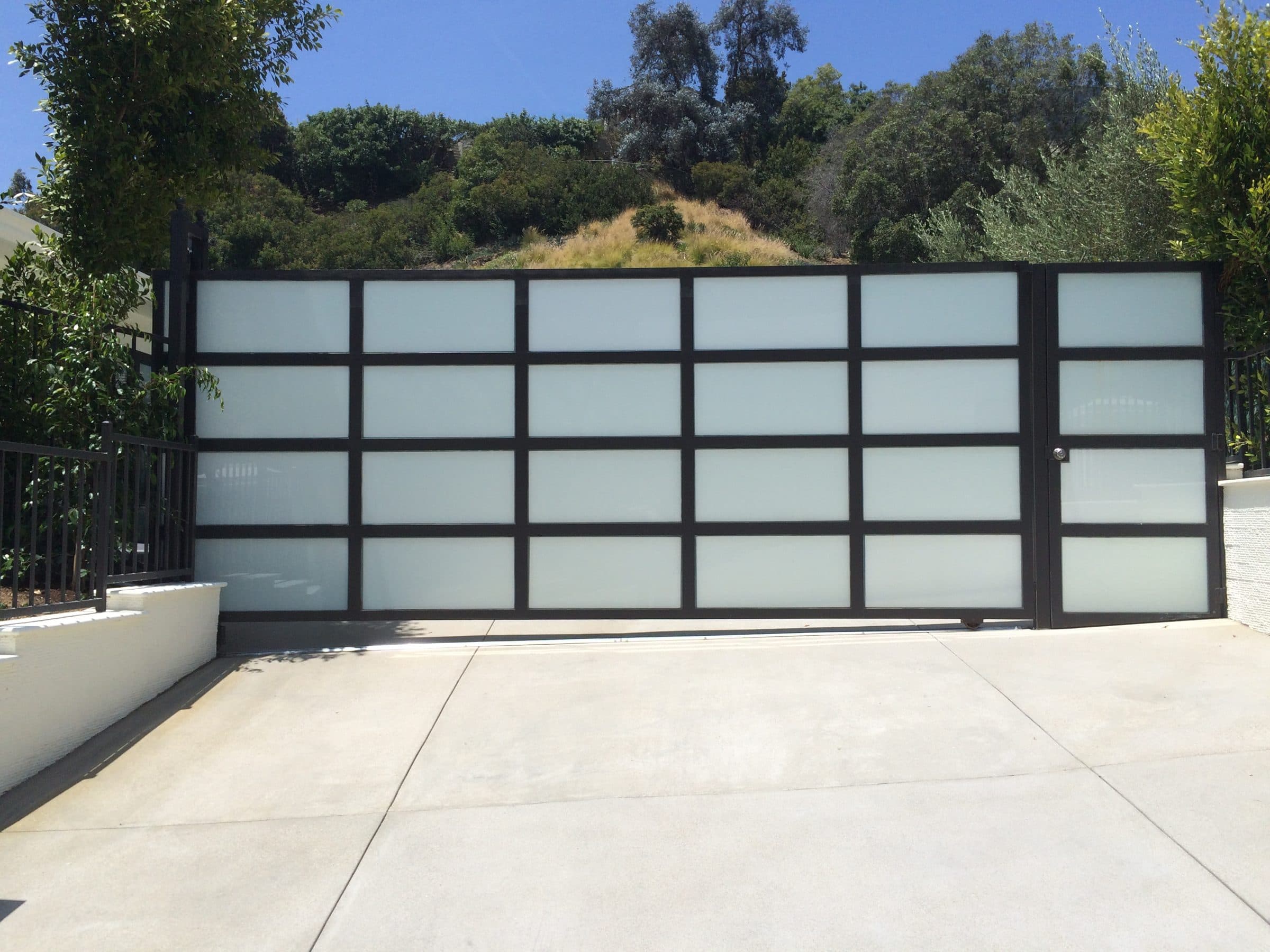Modern frosted glass sliding driveway gate installed in the San Fernando Valley