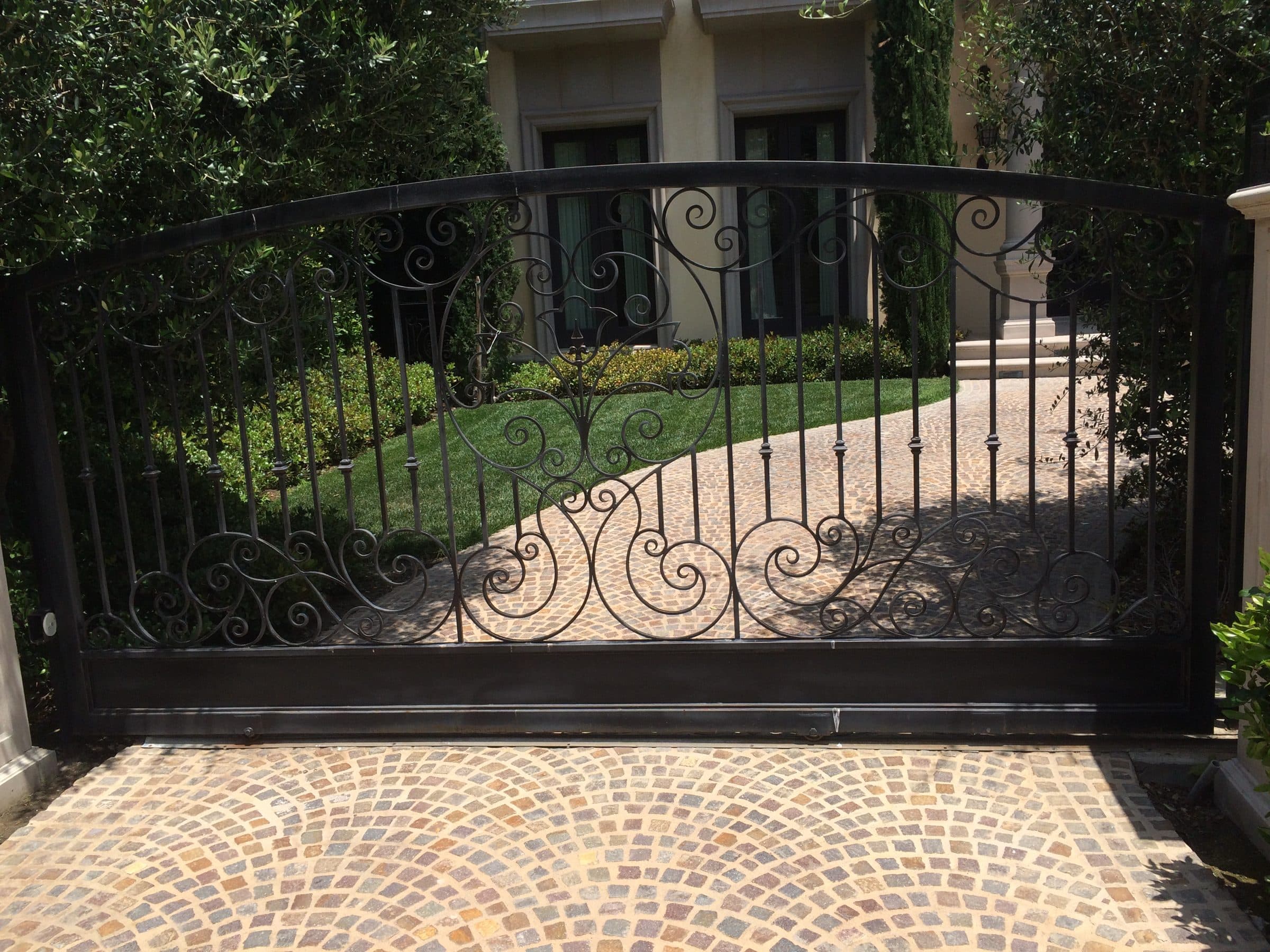 Hand-forged scroll gate on a brick driveway