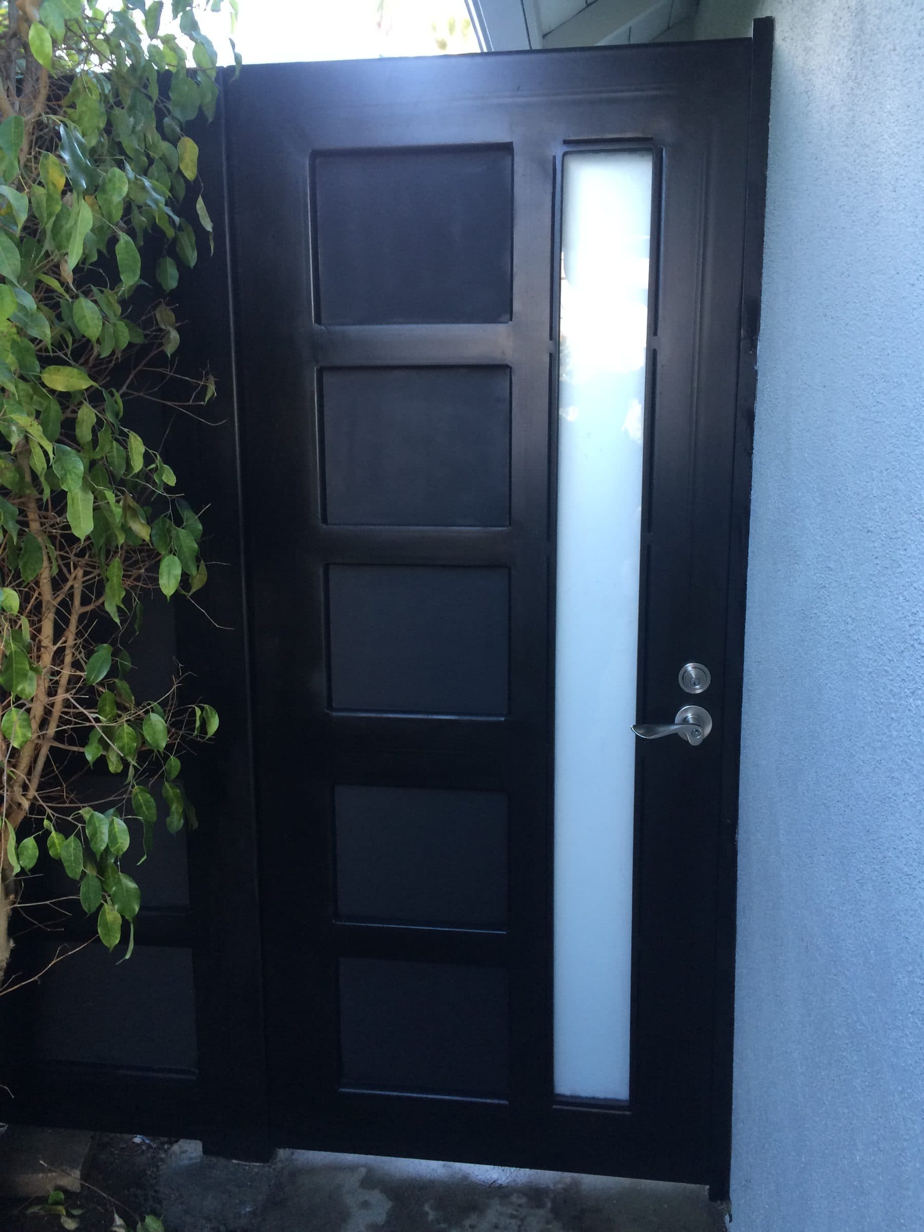 Modern black steel security door with frosted glass panel by J.V. General Construction
