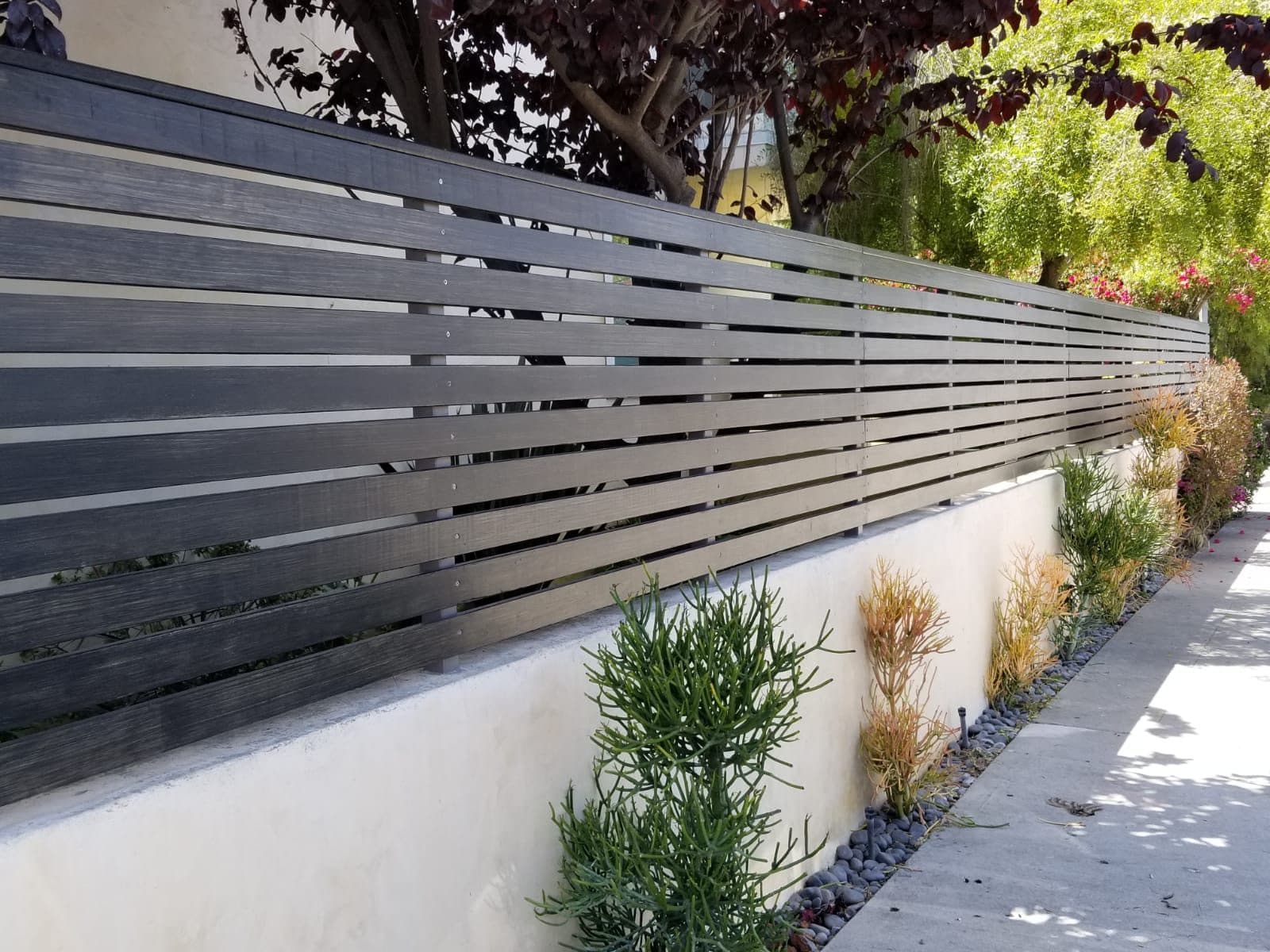 Modern horizontal slat fence installed along a landscaped parkway in Los Angeles