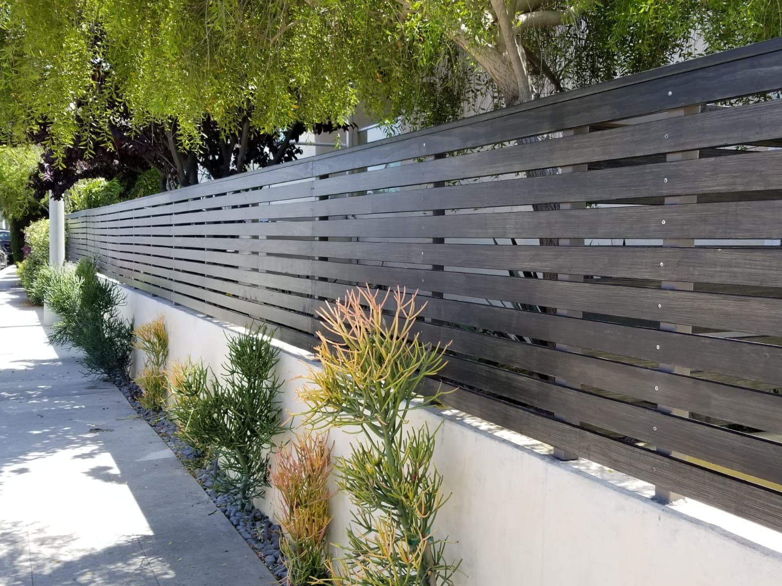 Long run of modern slat fencing along a sidewalk