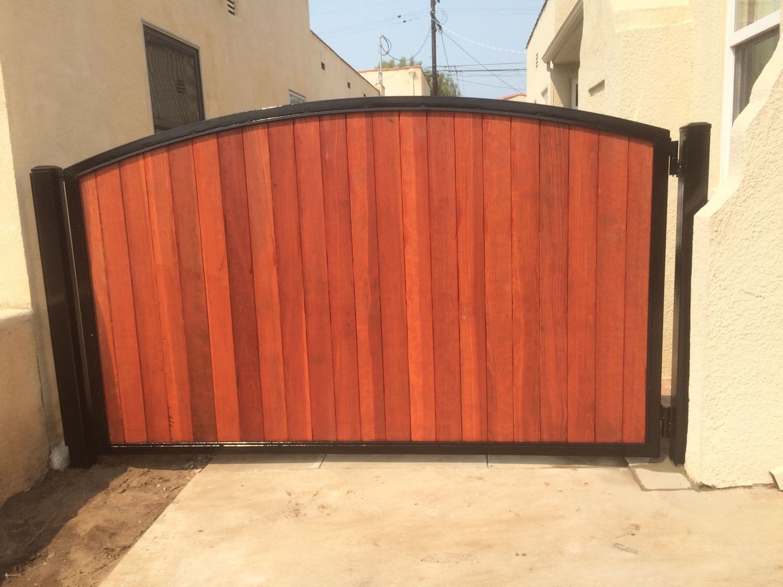 Redwood arched driveway gate with black steel frame